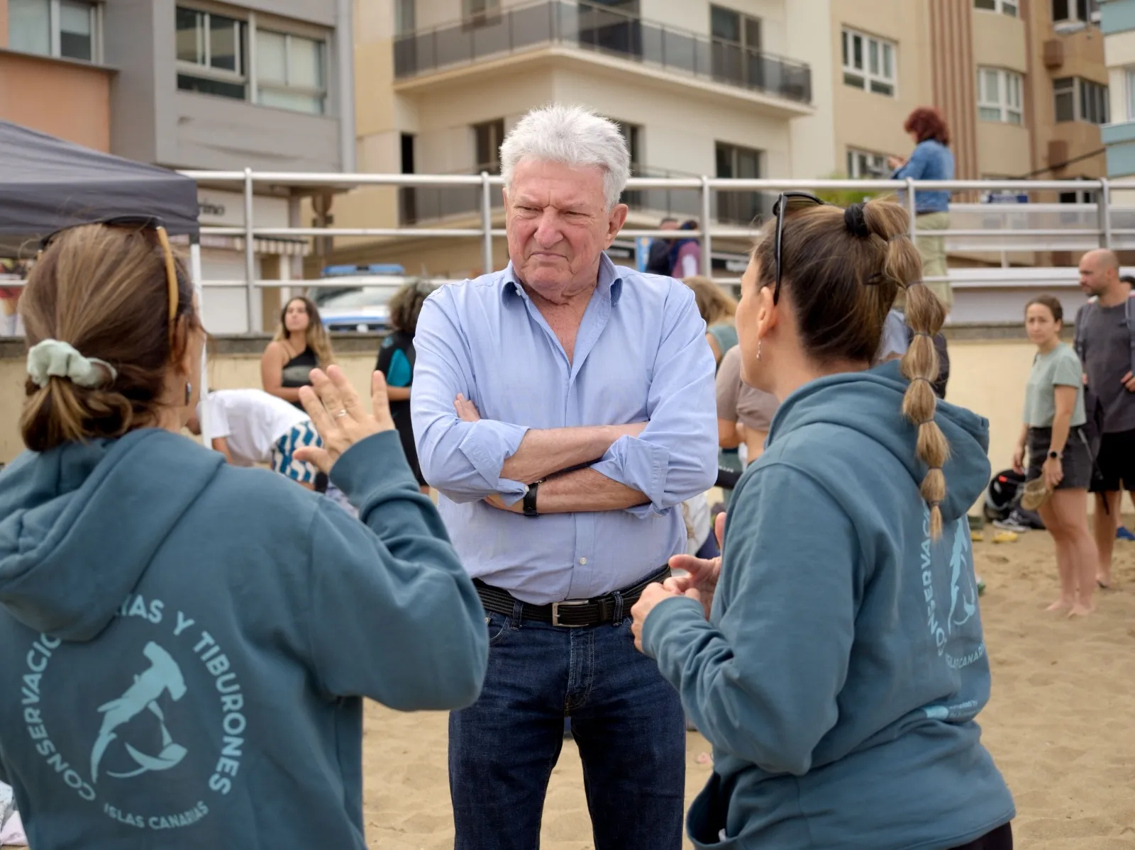 Grifo abierto llenando un vaso de cristal transparente frente a botellas de plástico azules en una mesa de madera