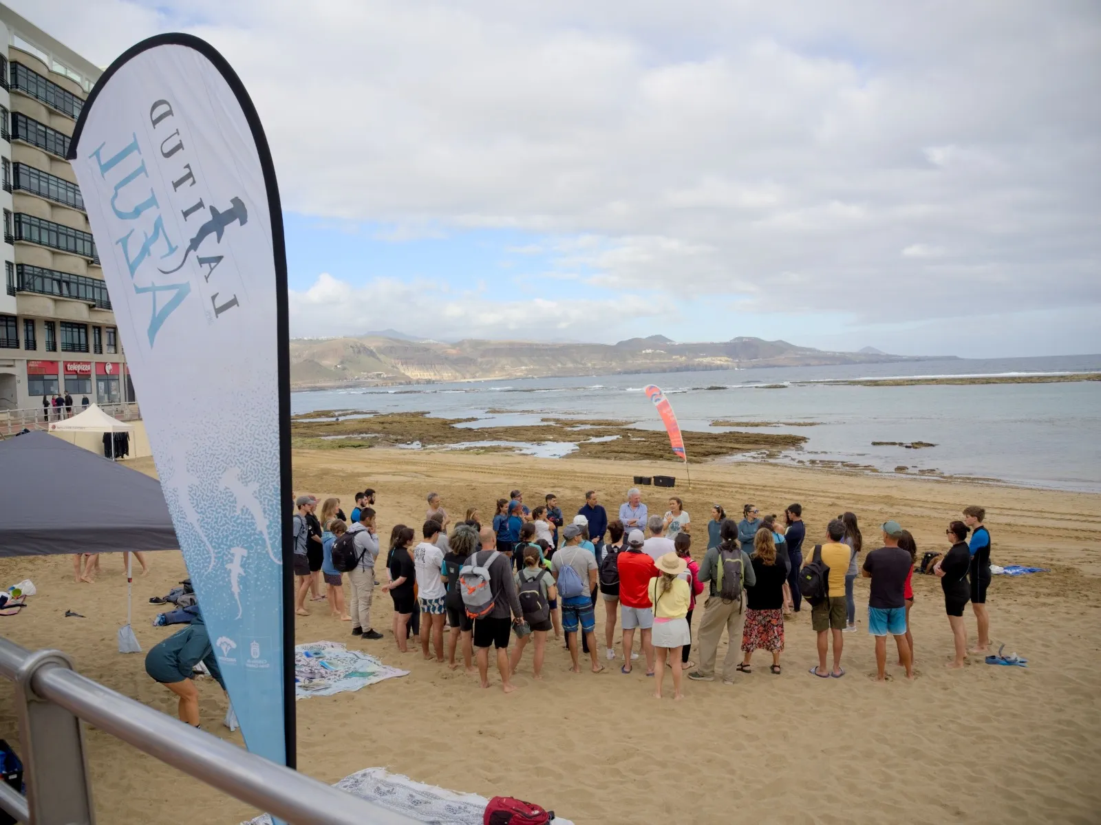 Cadena humana de cientos de personas cruzando la playa de Las Canteras con el océano Atlántico de fondo, unidas por la conservación marina
